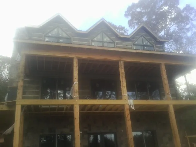 Dormers and porch framing on a large log home under construction — Roof Coating work by our crew in Chemung