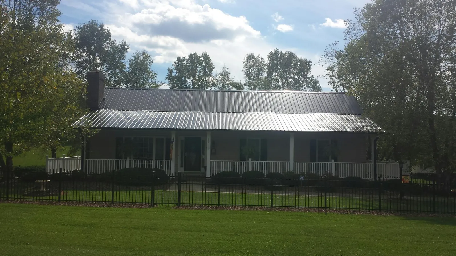 Gray metal roof on a brick ranch with a full width front porch — Gutter Guard Installation work by our crew in Chemung