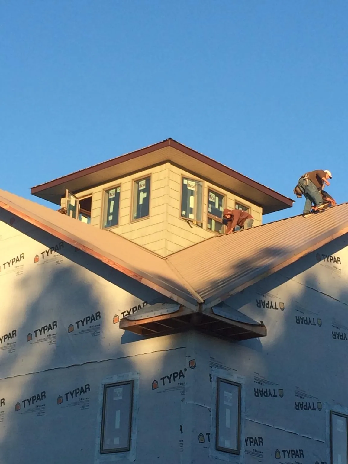 Roofers working around a rooftop cupola on a new metal roof at sunset — Roof Waterproofing in Chemung by Roofing Brothers